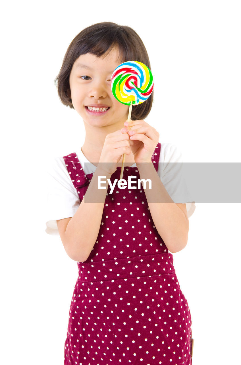 Portrait of smiling girl holding multi colored lollipop against white background