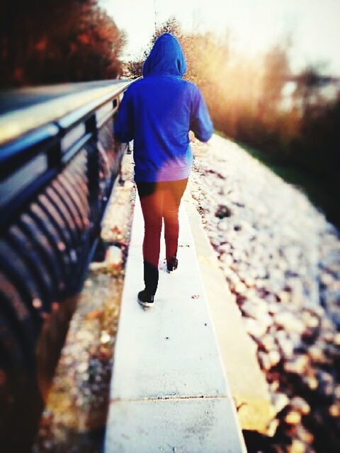 FULL LENGTH OF YOUNG WOMAN STANDING ON RAILING