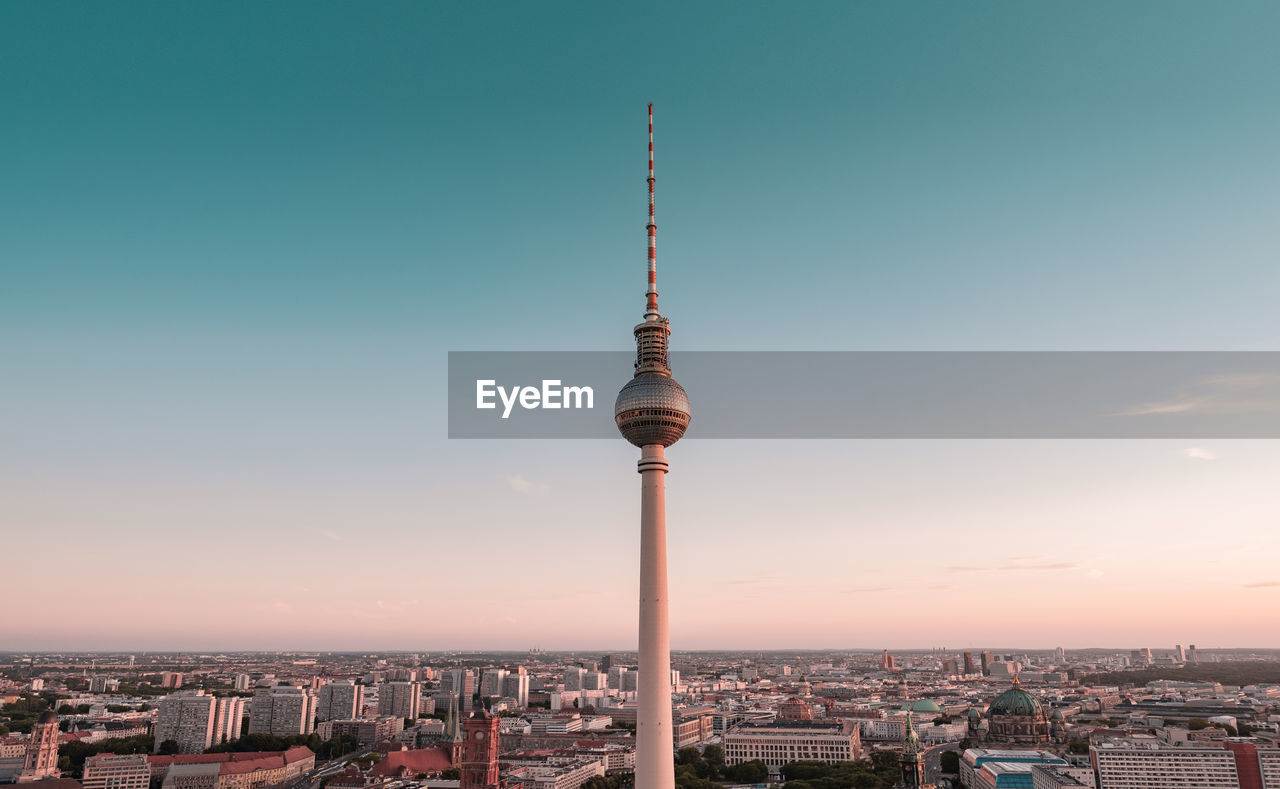 TOWER AMIDST BUILDINGS AGAINST SKY DURING SUNSET