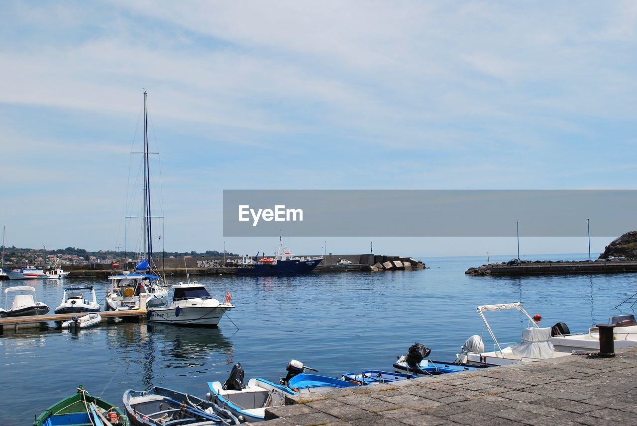 Boats moored at harbor against sky