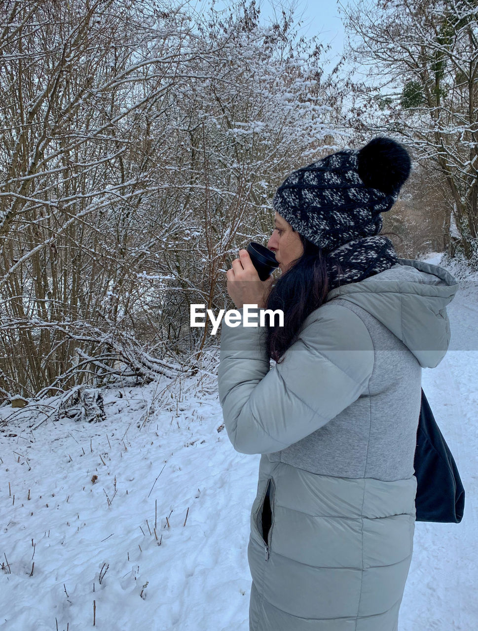 WOMAN STANDING ON SNOW COVERED LAND