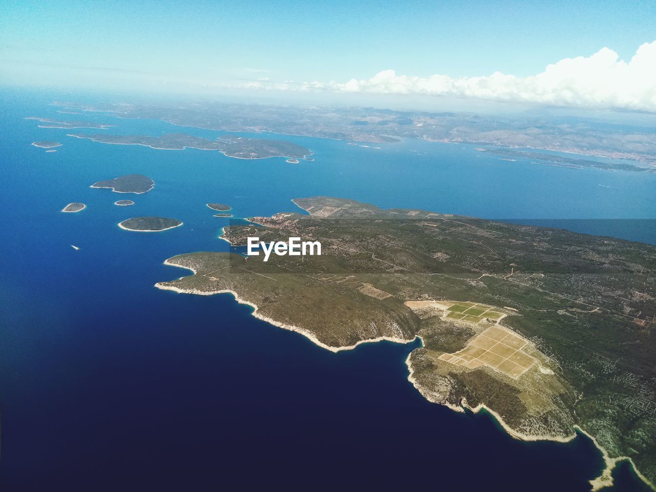 AERIAL VIEW OF ISLAND AGAINST BLUE SKY