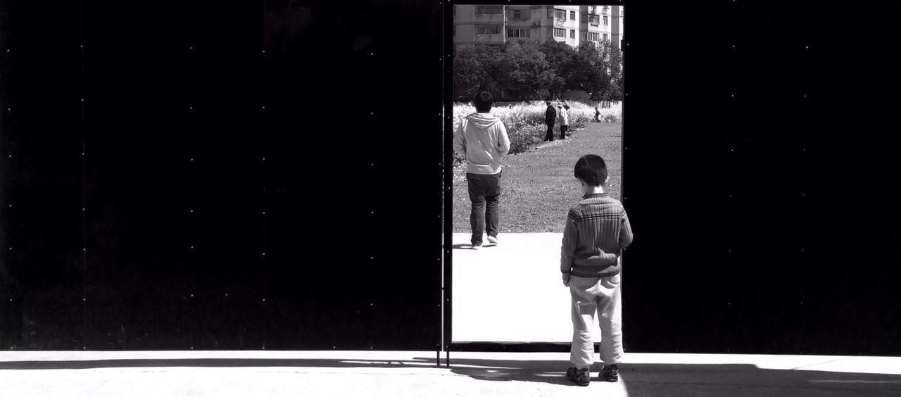 Rear view of boy standing in front of black gate