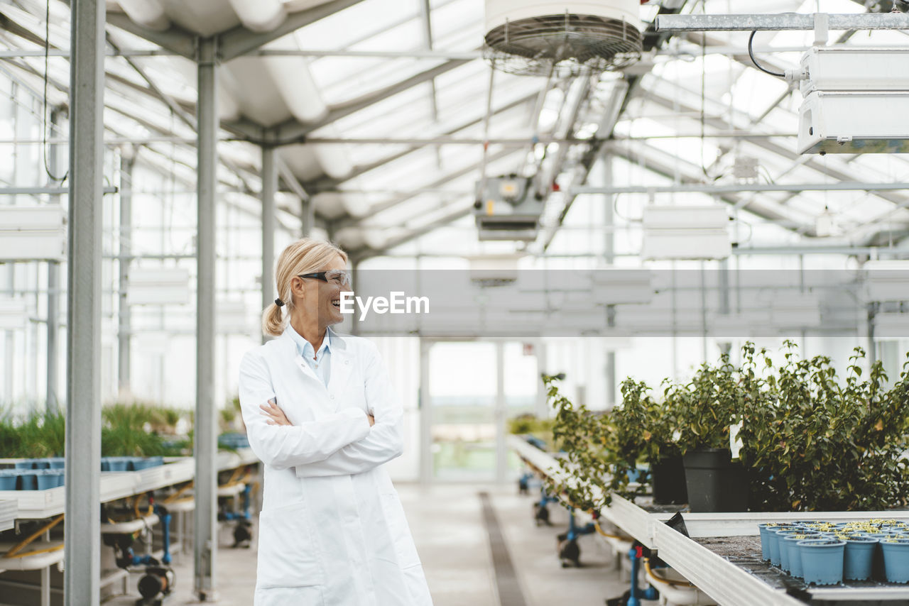 Cheerful scientist with arms crossed in plant nursery