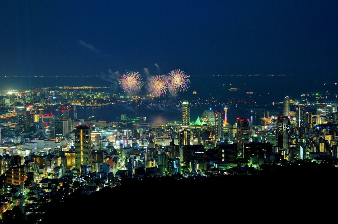 Aerial view of illuminated cityscape and sea against sky at night