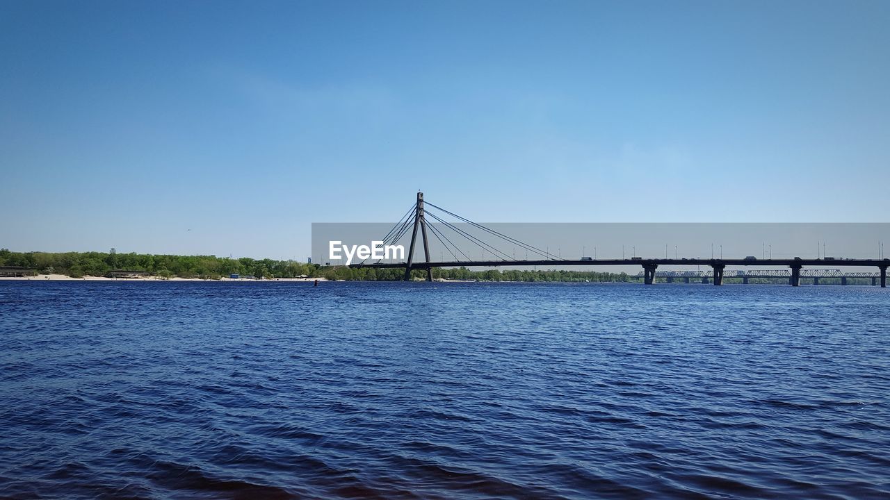 Bridge over sea against clear blue sky