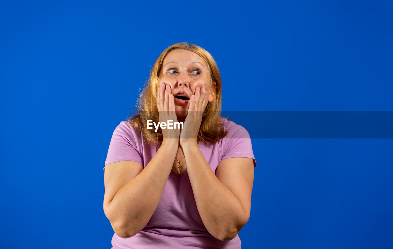 PORTRAIT OF WOMAN AGAINST BLUE BACKGROUND