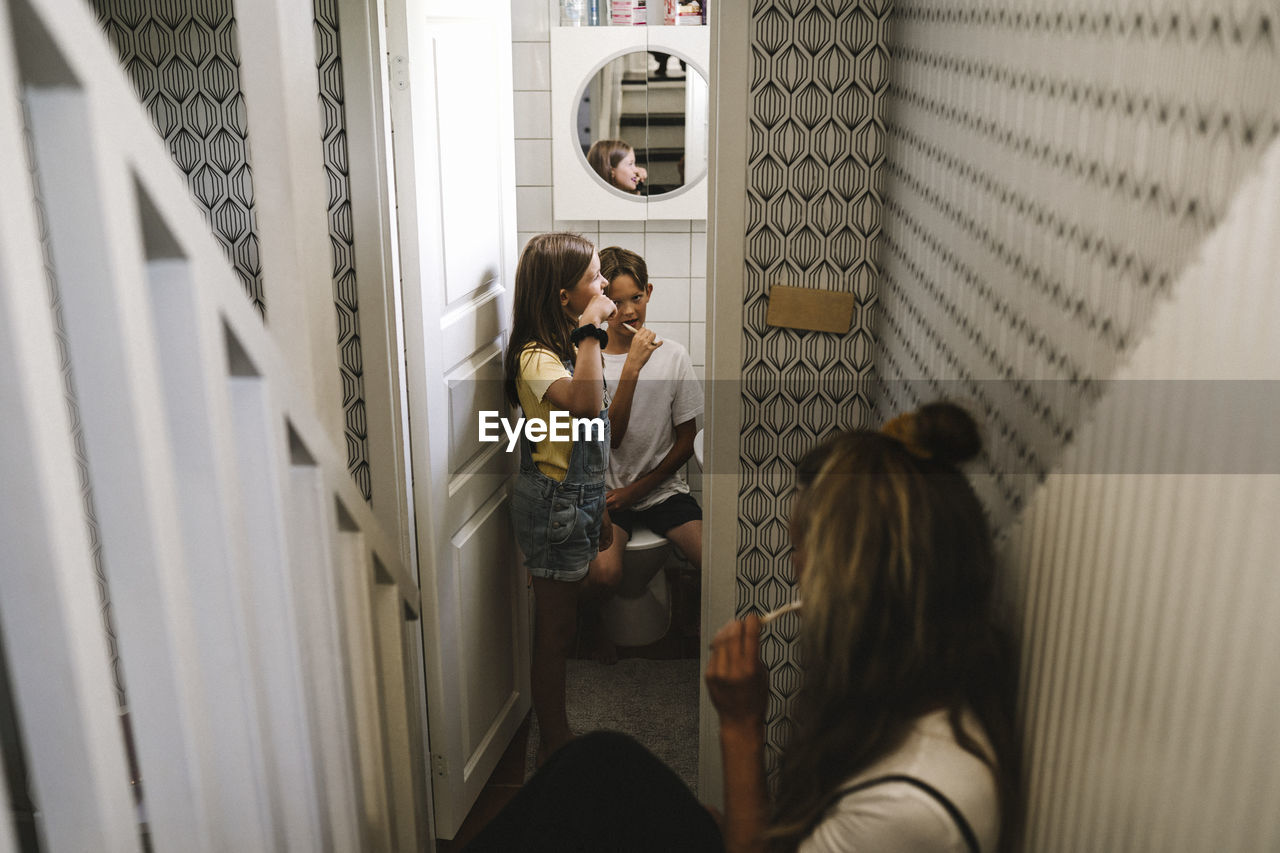 Mother with children brushing teeth in bathroom