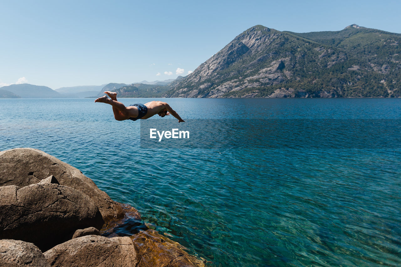 SCENIC VIEW OF SEA BY MOUNTAIN AGAINST CLEAR SKY