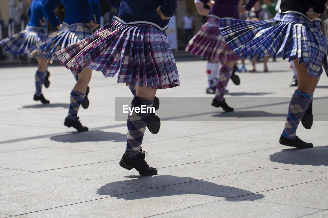 Low section of women dancing on footpath