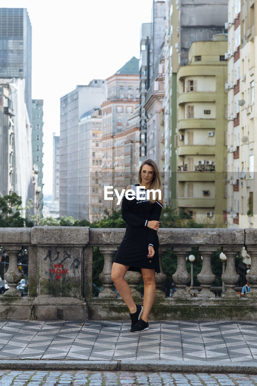 Portrait of woman standing against buildings in city