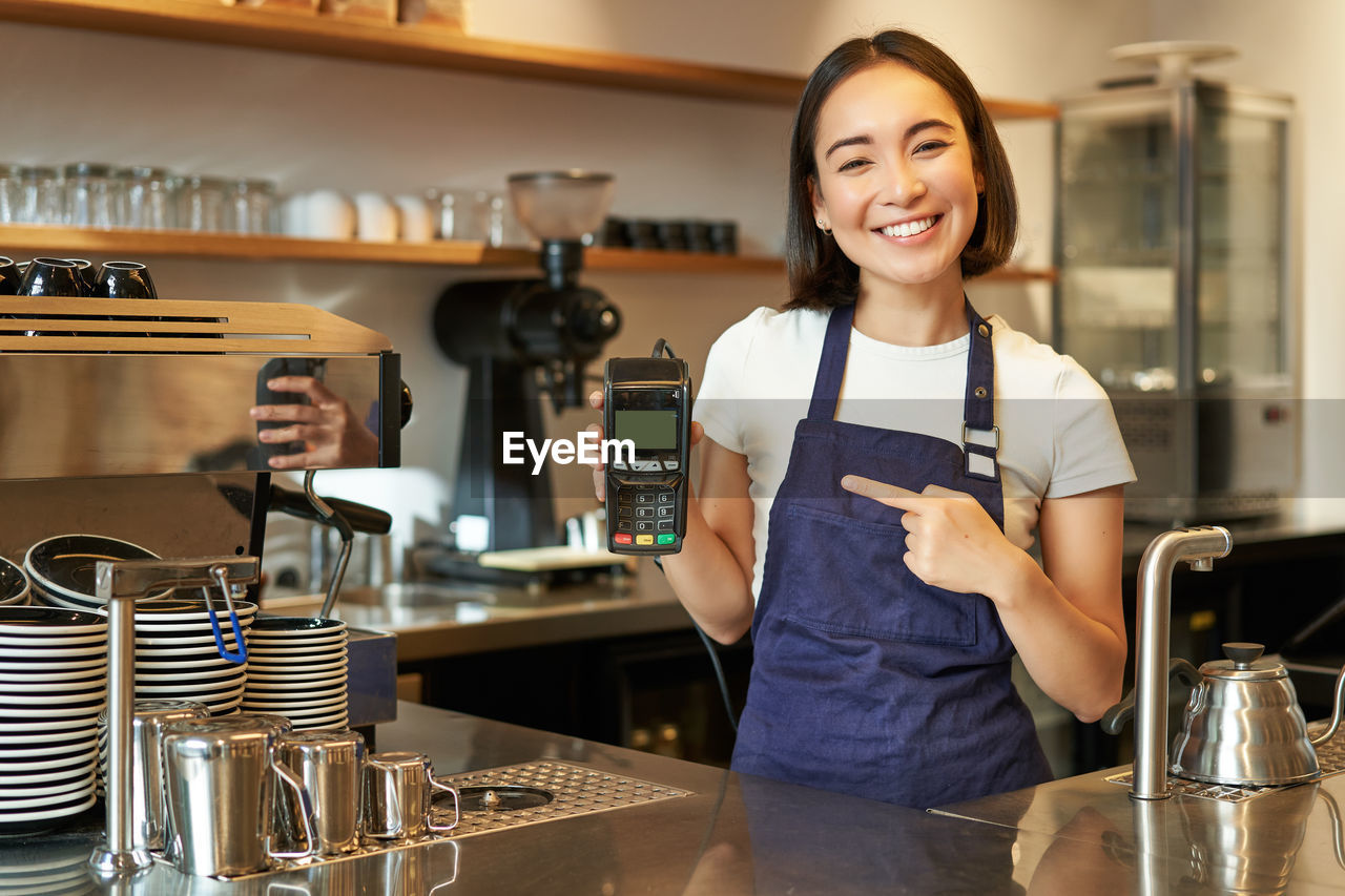 portrait of smiling young woman standing in kitchen