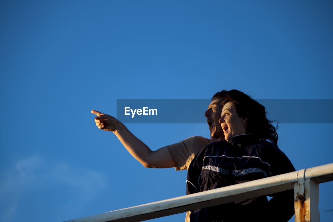 Man pointing with woman against blue sky