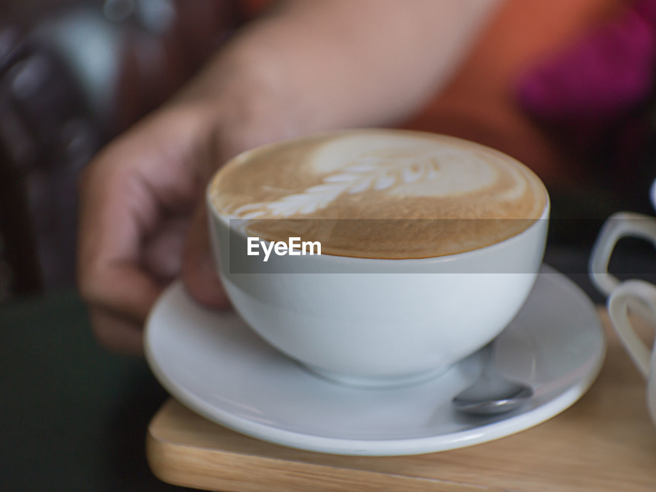 Cropped hand of person with coffee at table