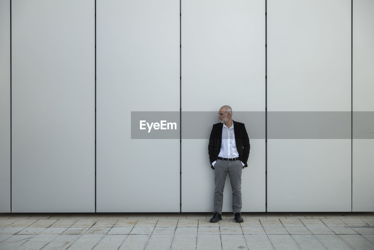 Portrait of adult man in suit against white wall in financial district