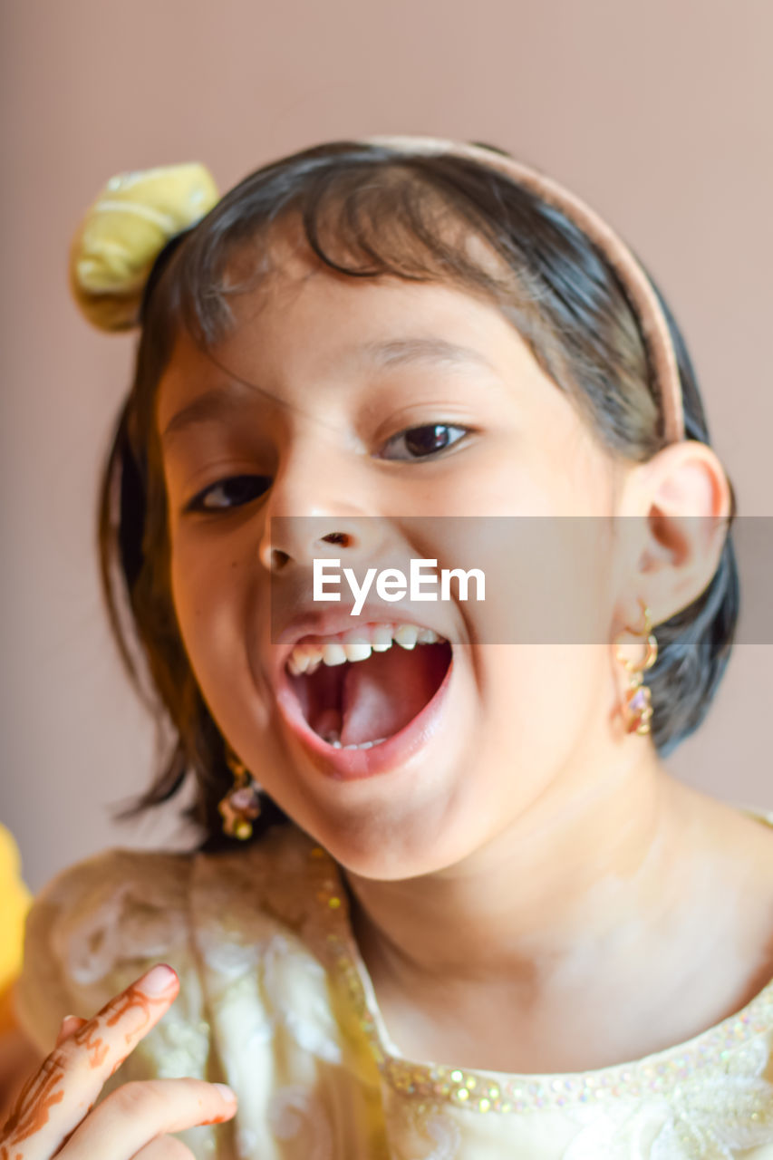 Close-up portrait of cheerful girl wearing headband at home