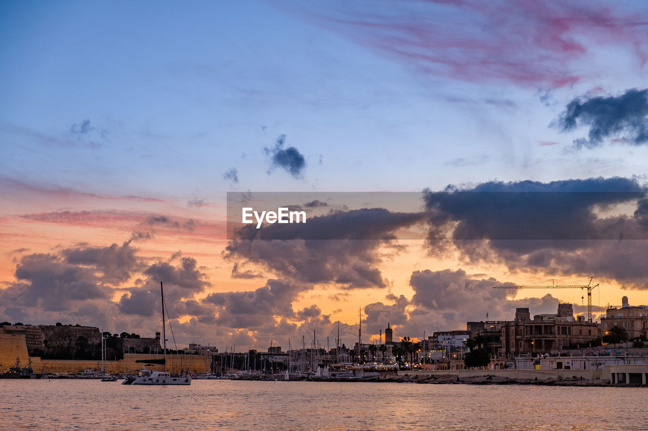 Panoramic view of sea and buildings against sky during sunset