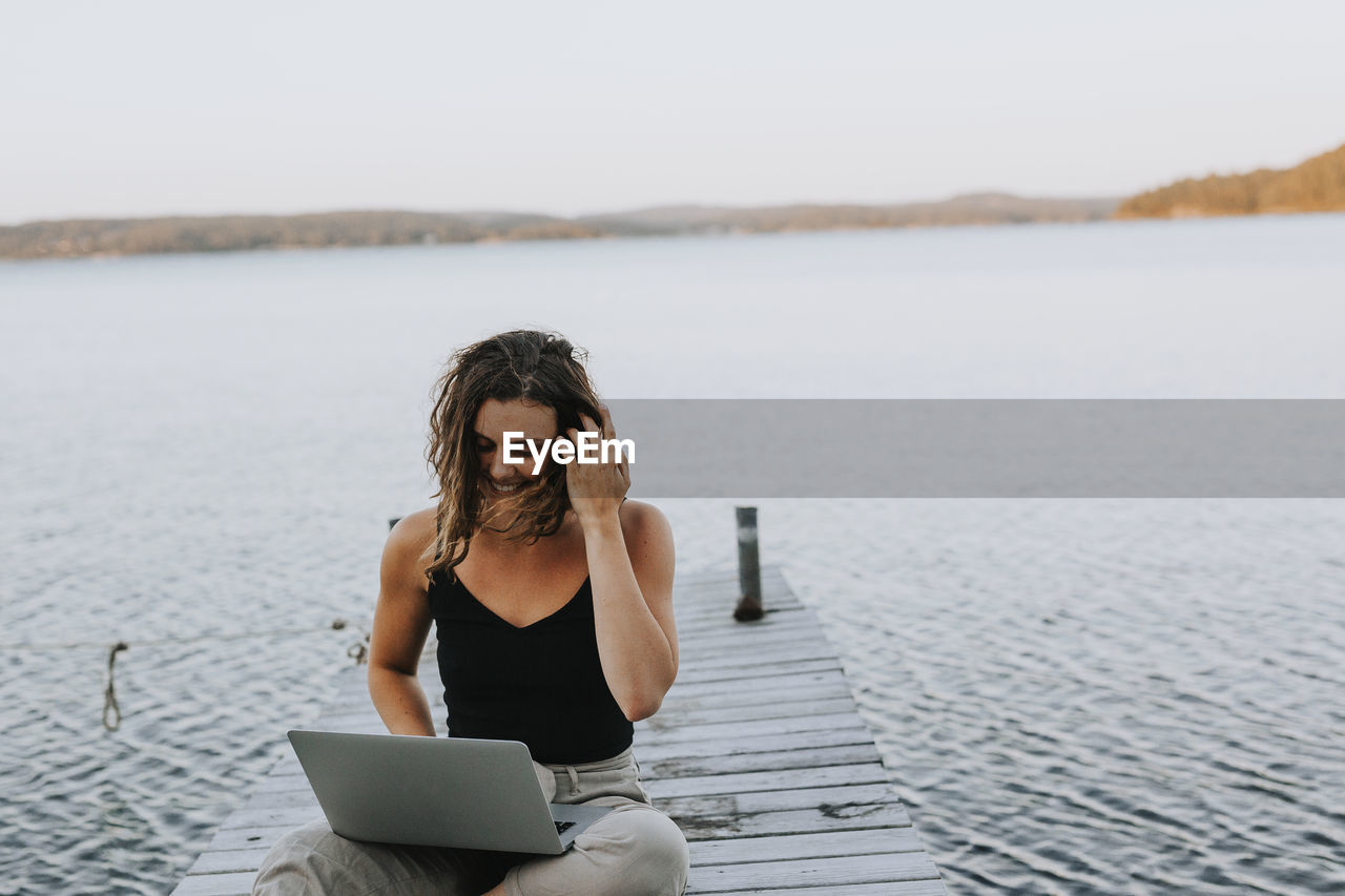 Woman on jetty using laptop