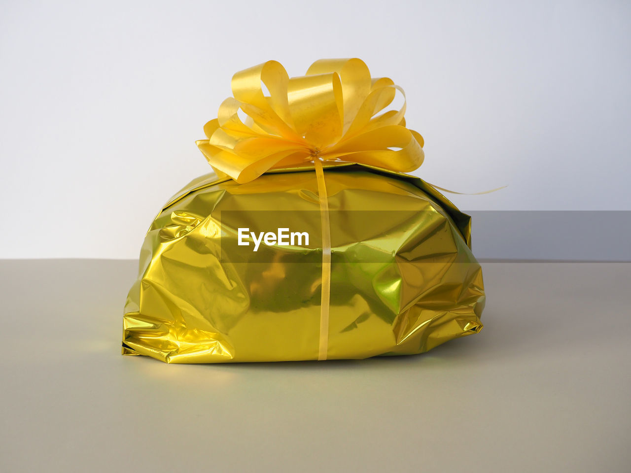 yellow, gift, ribbon, bow, tied bow, celebration, present, gold, wrapping paper, surprise, box, wrapped, holiday, gift box, paper, christmas, studio shot, indoors, container, single object, event, no people, copy space, wedding favors, birthday present, shiny, art, emotion, decoration, still life, anniversary, birthday, cut out, petal, party favor
