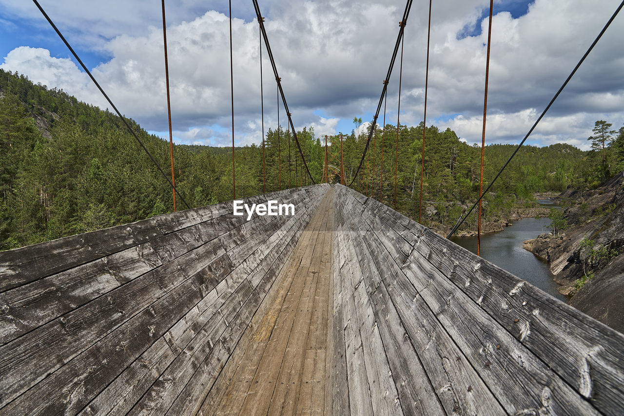 cloud, sky, nature, bridge, wood, tree, environment, transportation, plant, scenics - nature, landscape, land, no people, track, suspension bridge, the way forward, beauty in nature, mountain, outdoors, tranquility, day, forest, diminishing perspective, travel, non-urban scene, tranquil scene, road, travel destinations, architecture, water, infrastructure, built structure, tourism, cable, transport, vanishing point, rope