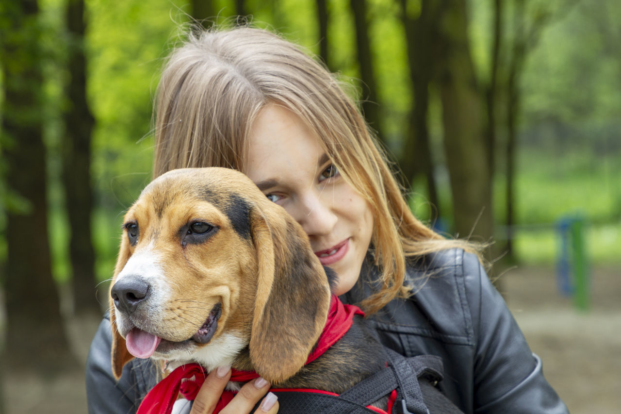 PORTRAIT OF WOMAN WITH DOG AGAINST BLURRED BACKGROUND