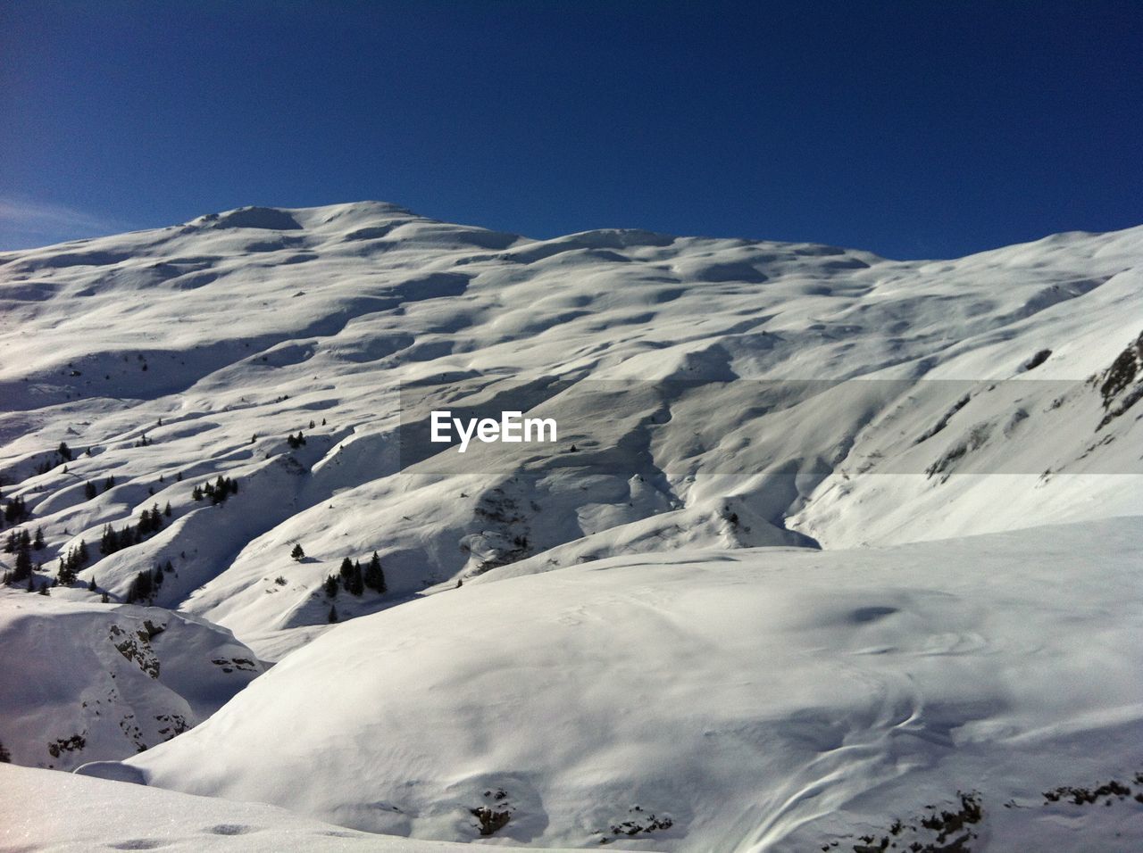 Scenic view of snowcapped mountains against clear blue sky