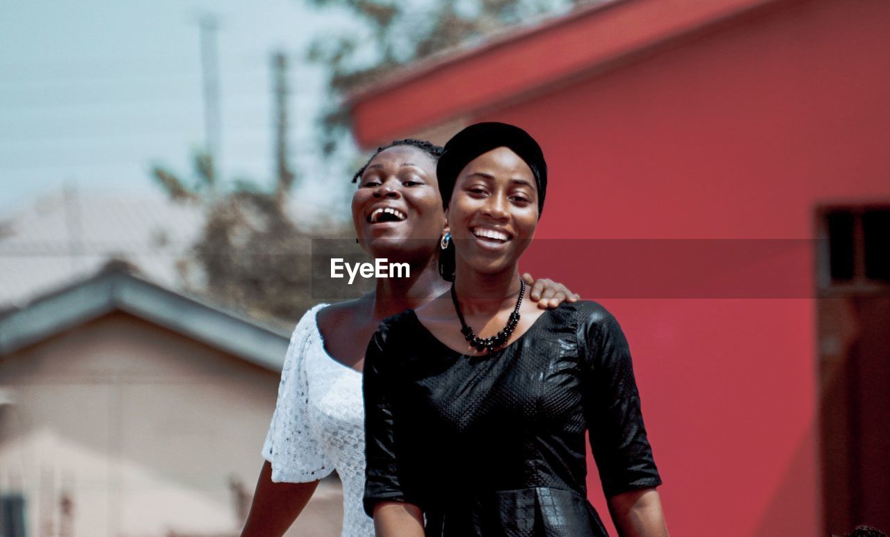 Portrait of smiling friends with arm around in city