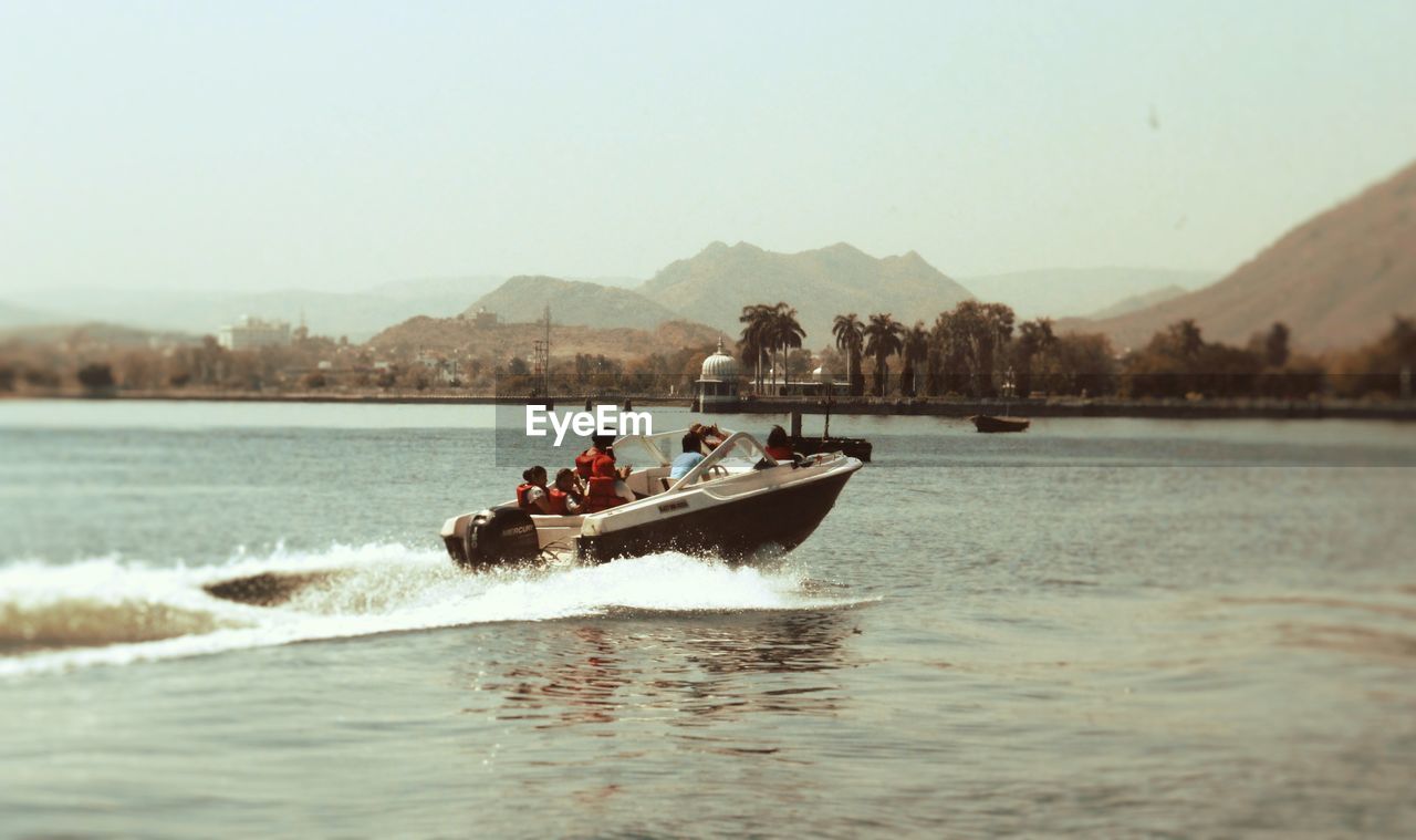 PEOPLE SAILING ON RIVER AGAINST CLEAR SKY