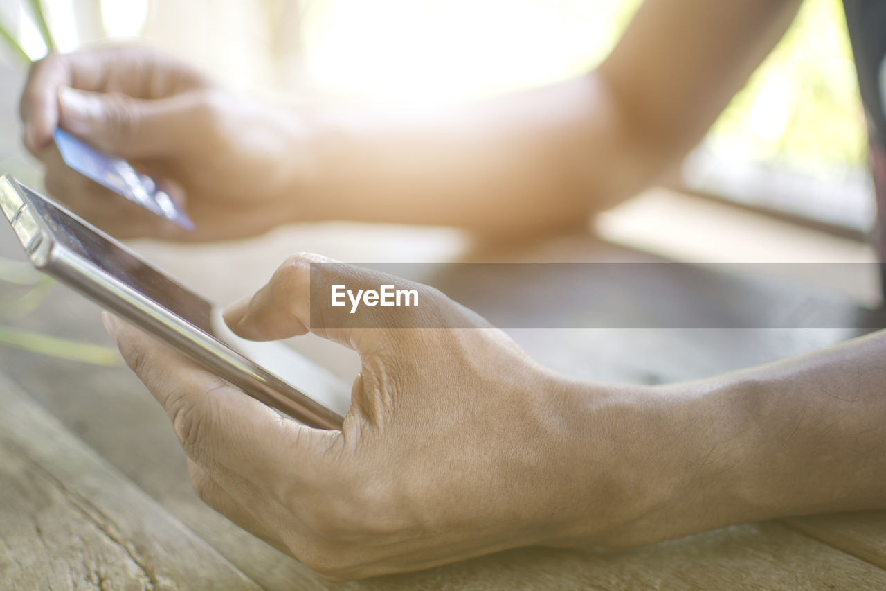 Cropped hands of man using mobile phone at table