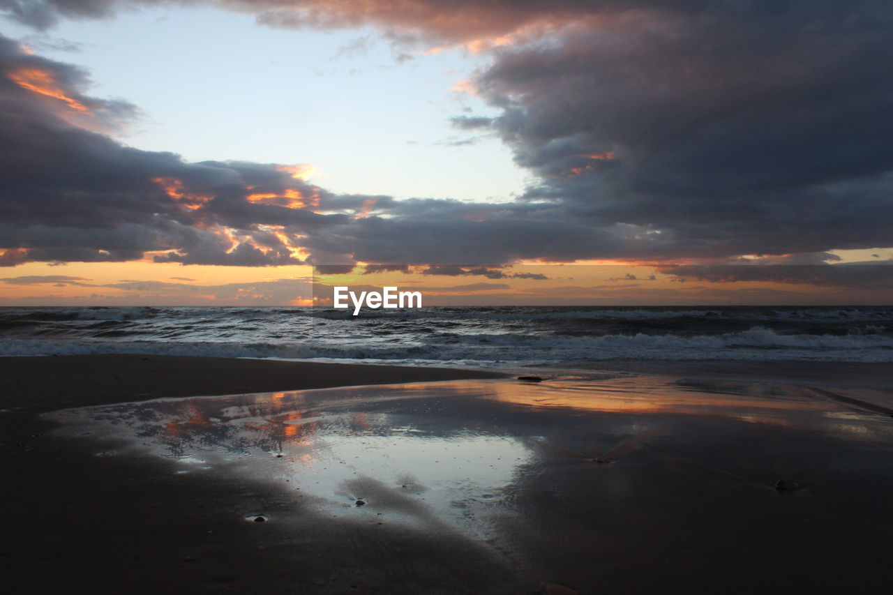 scenic view of sea against cloudy sky during sunset