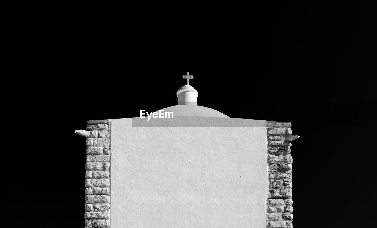 Religious cross over building against sky at night