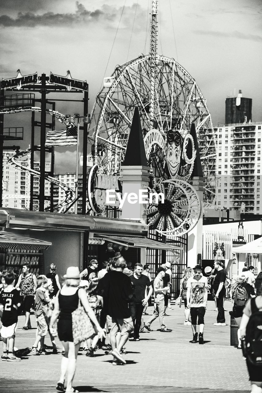 People at amusement park against sky