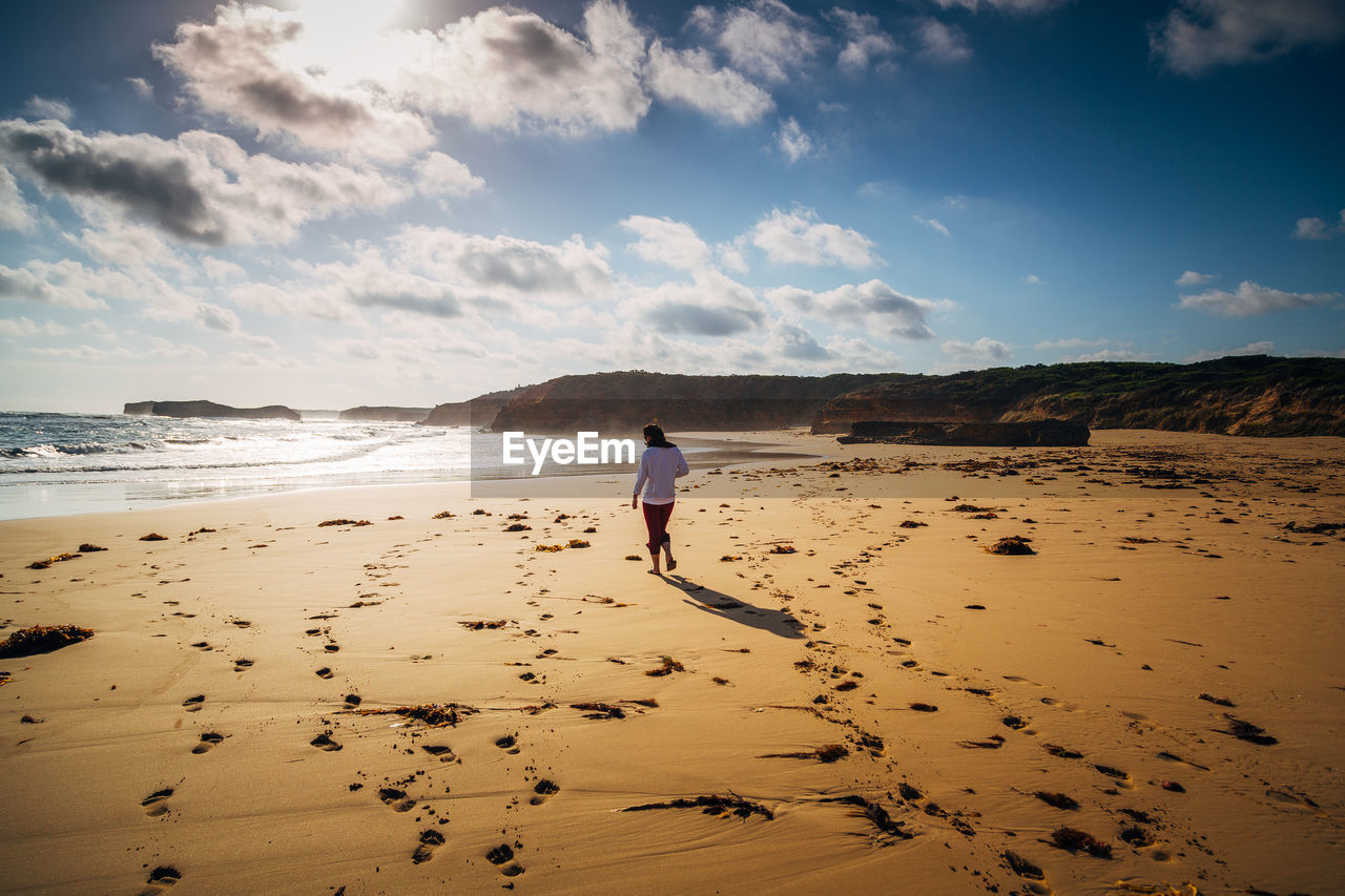 Rear view of woman on beach against sky