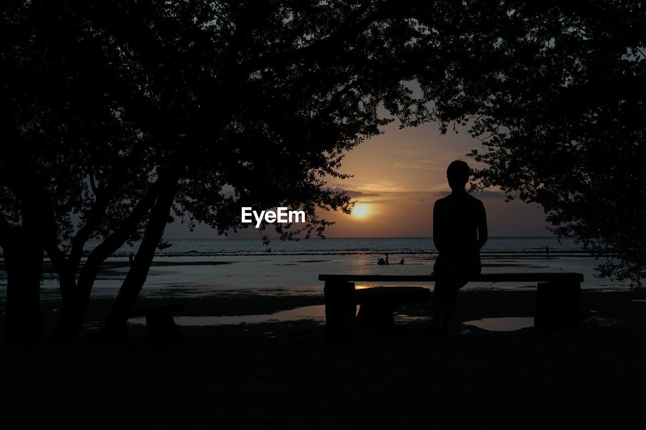 SILHOUETTE MAN LOOKING AT SEA AGAINST SKY DURING SUNSET