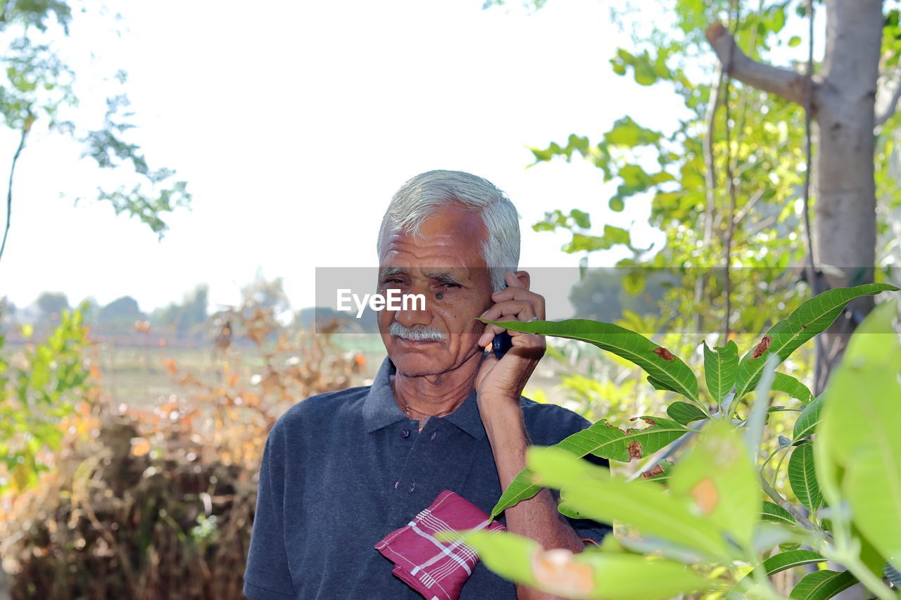  farmer or gardener standing in a field talking to an agricultural  specialist on a keypad mobile