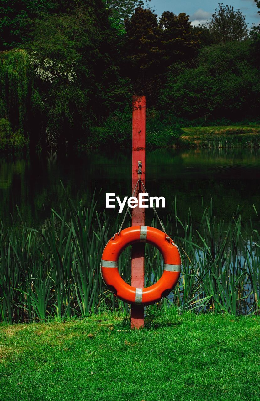 Life belt hanging from wooden pole against river