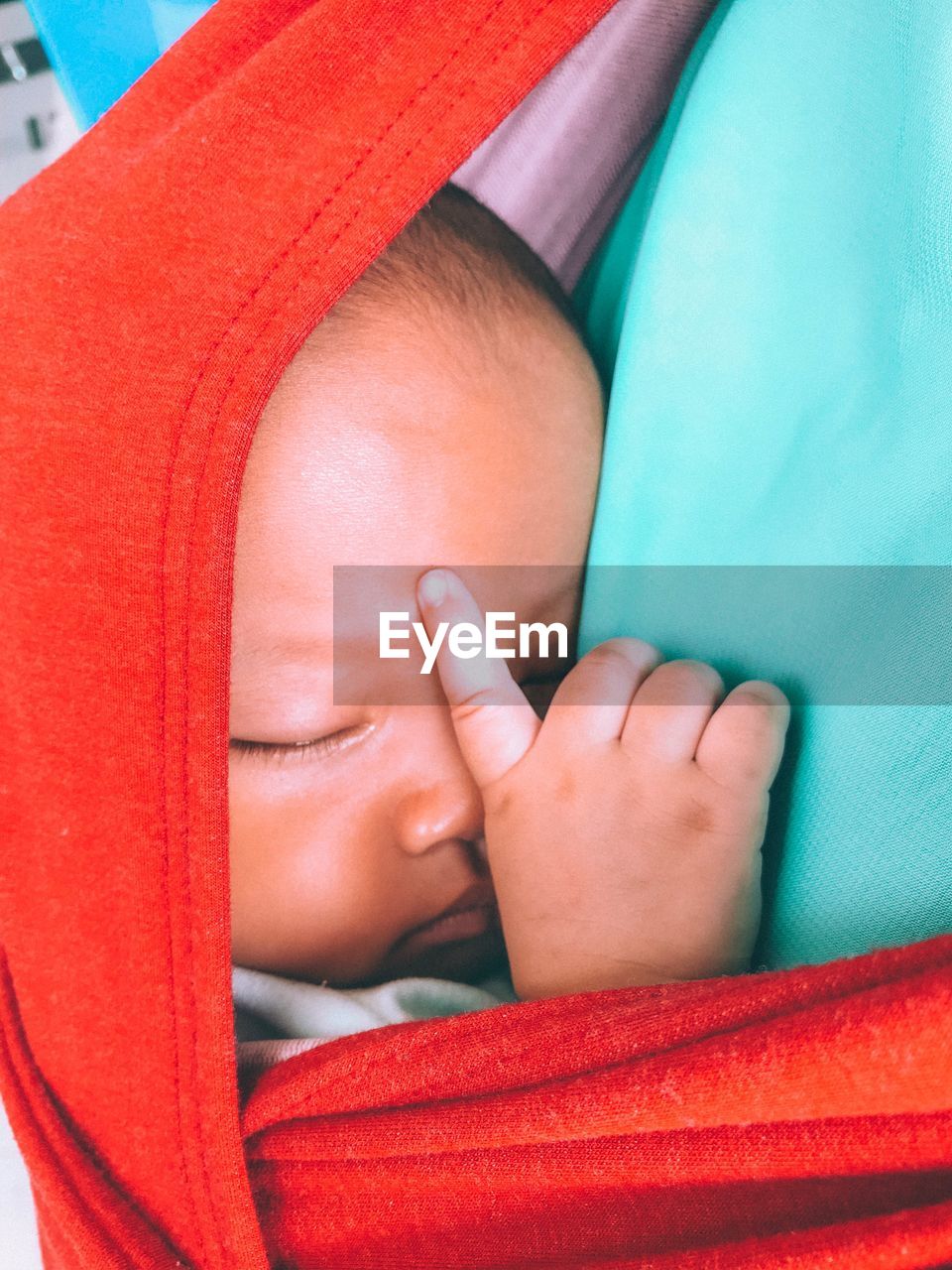 CLOSE-UP OF BABY GIRL LYING ON RED BLANKET