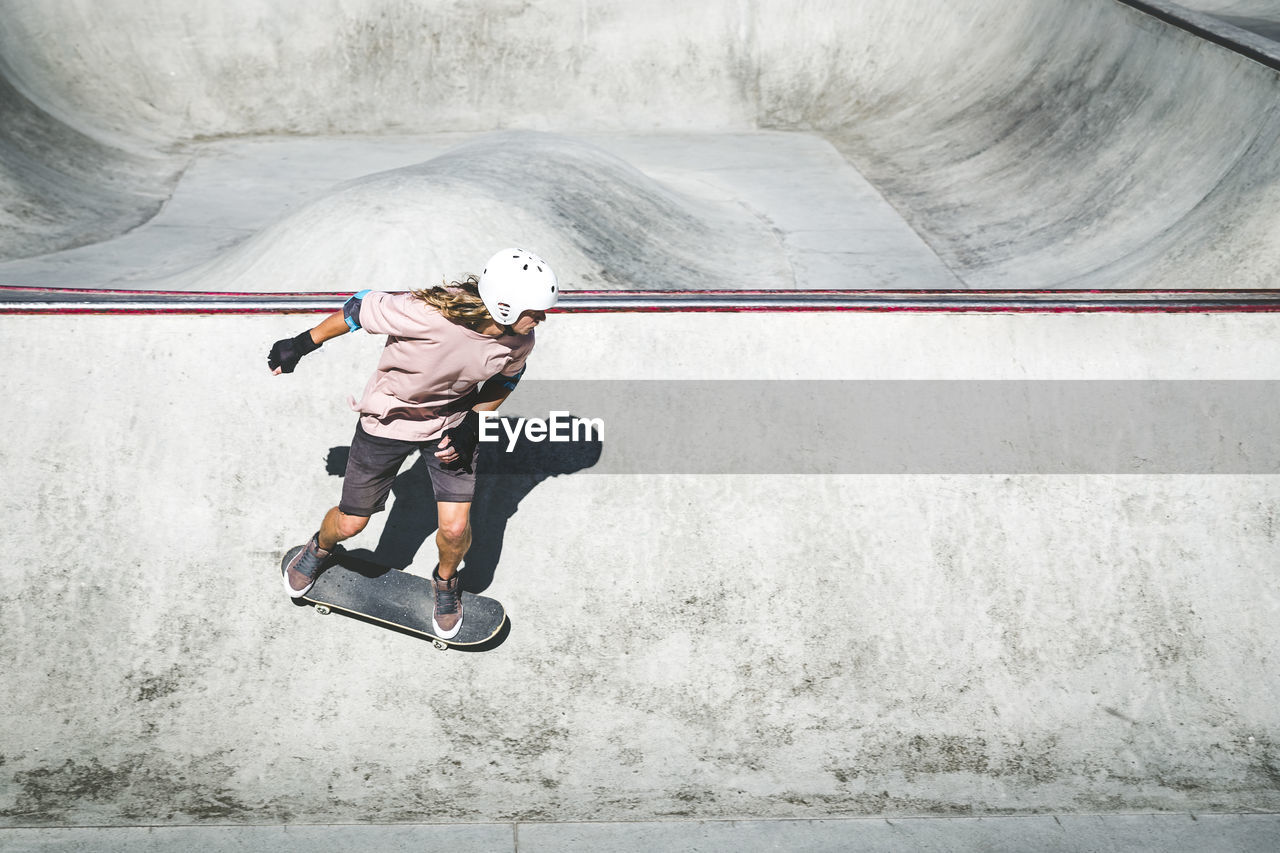 Mid adult sportsman skating at skateboard park during sunny day