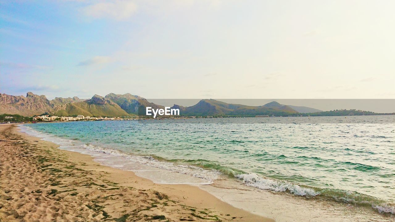 SCENIC VIEW OF BEACH BY MOUNTAINS AGAINST SKY