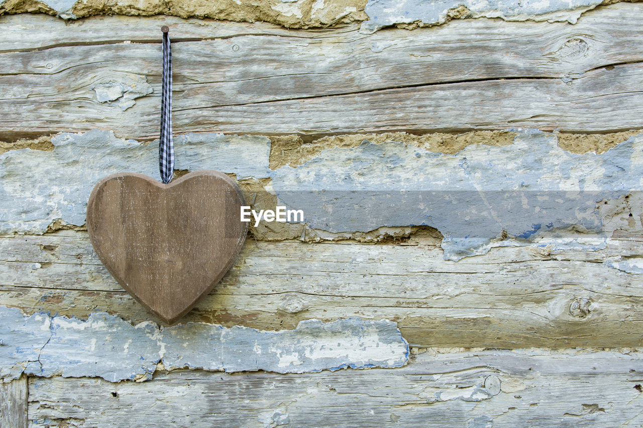 CLOSE-UP OF HEART SHAPE ON WOOD AGAINST BRICK WALL