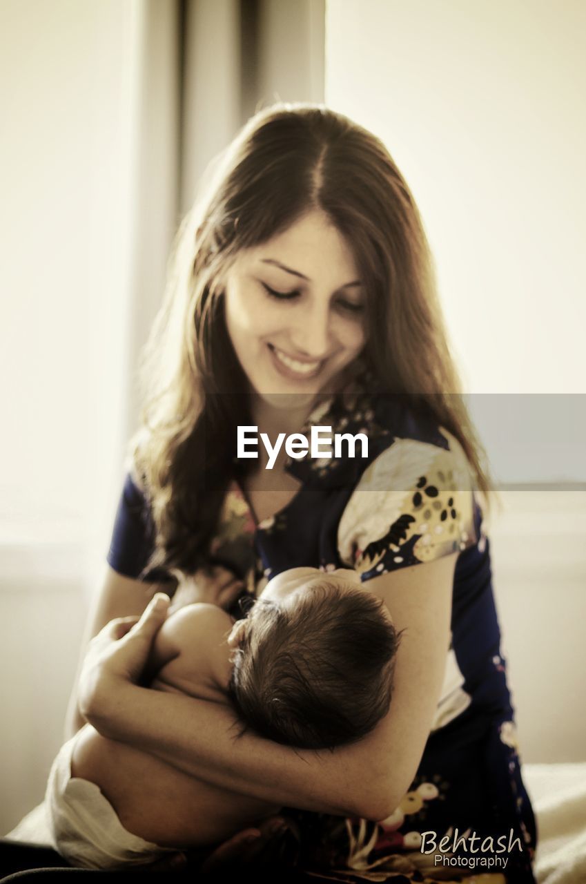 CLOSE-UP OF MOTHER WITH BABY SITTING ON WALL