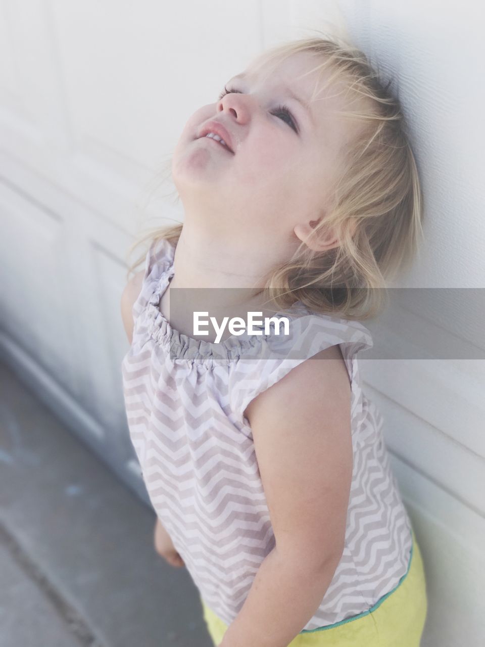 Girl looking up while standing by wall