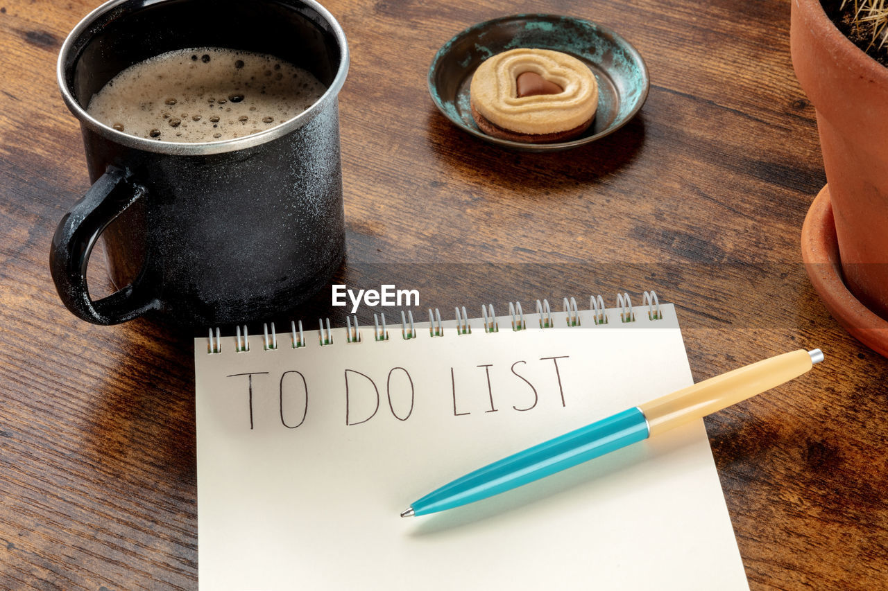 HIGH ANGLE VIEW OF COFFEE CUP WITH TEXT ON TABLE