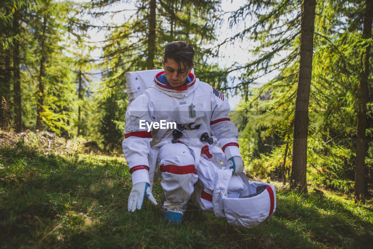 Curious astronaut crouching in forest