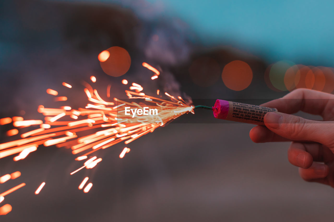 CLOSE-UP OF PERSON HOLDING SPARKLER AT NIGHT