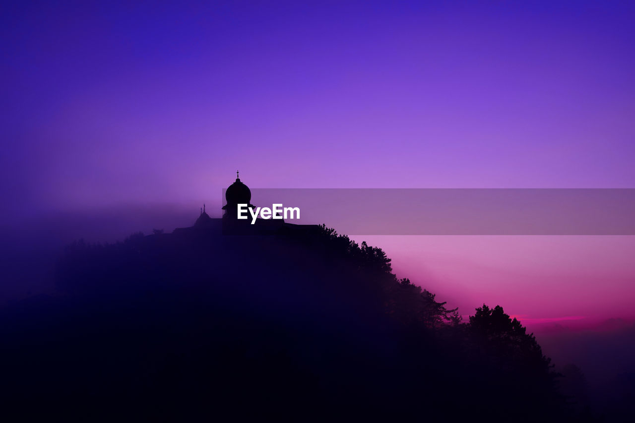 Silhouette temple on mountain against sky at dusk