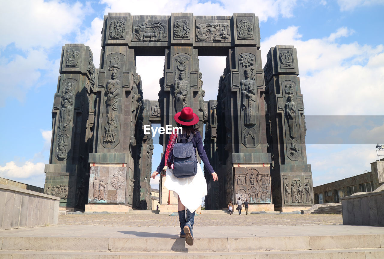 Female impressed by the chronicle of georgia, a gigantic 30 meter tall monument, tbilisi, georgia