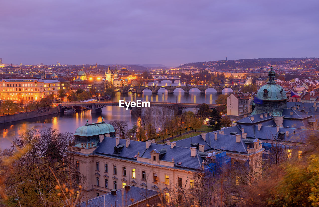 High angle view of bridges over river in illuminated city at dusk