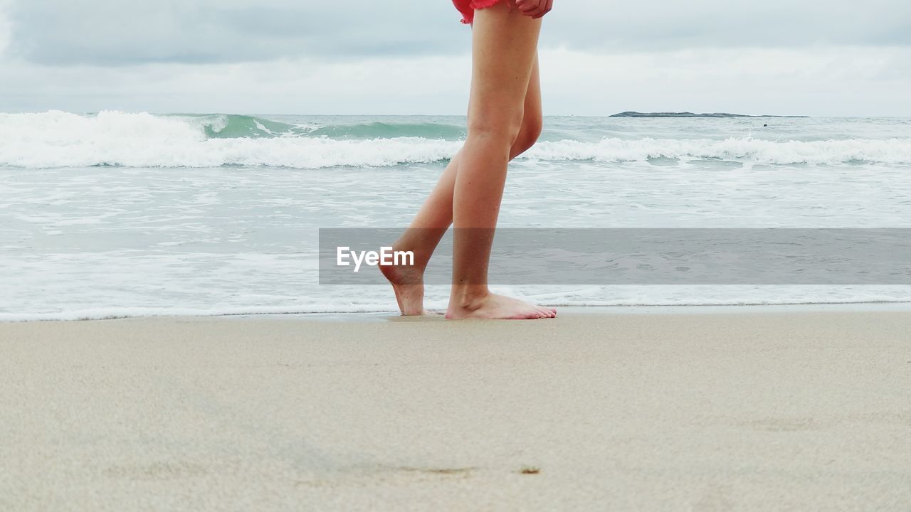 Low section of woman on shore of beach