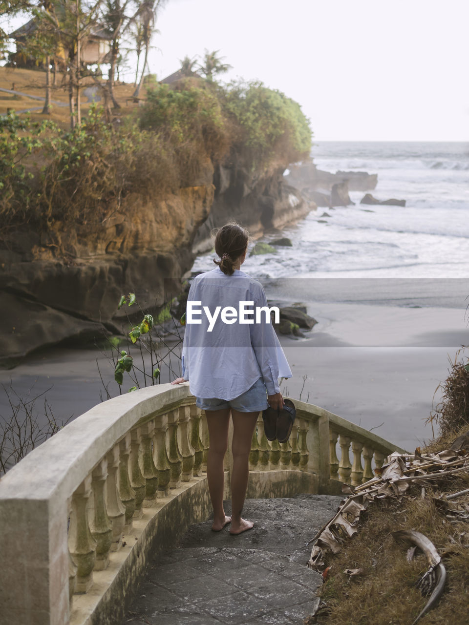 Rear view of woman walking down steps at beach